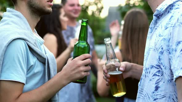 Two Men Are Talking Separately From the Company, Holding Bottles of Beer in Their Hands