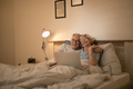 Happy mature couple having fun while using laptop in bedroom. - PhotoDune Item for Sale