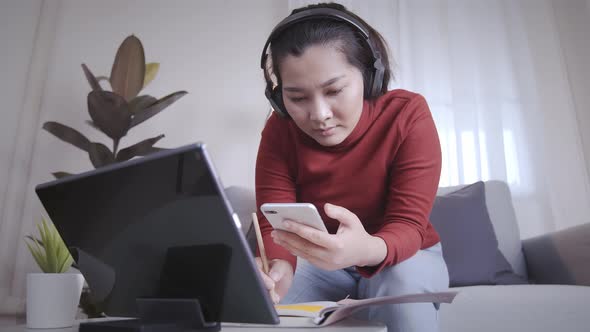 Freelance woman redshirt using tablet with headphone for meeting online at home