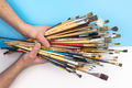 Paint brushes in male hands on a colored background, top view. - PhotoDune Item for Sale