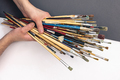 Paint brushes in male hands on a colored background, top view. - PhotoDune Item for Sale
