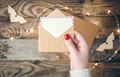 Blank postcard and envelope in female hands on a blurred wooden background. - PhotoDune Item for Sale