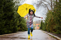 Baby Boomers and mental health. Happy senior woman in yellow rain coat with yellow umbrella jumping - PhotoDune Item for Sale