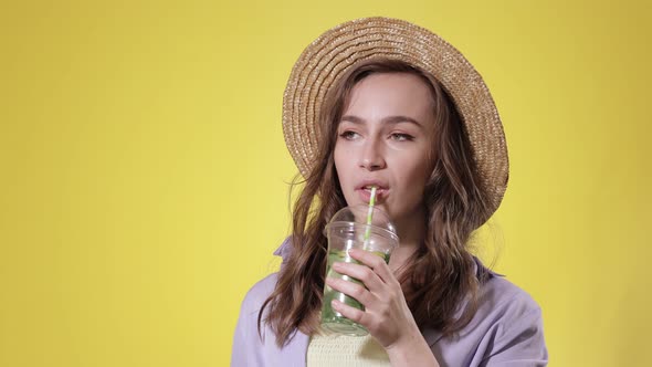Surprised Woman Drink Mojito cocktail From Plastic Cup Over Yellow Studio Background
