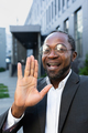 Smiling african american man in suit and glasses standing near office center talking on video call - PhotoDune Item for Sale