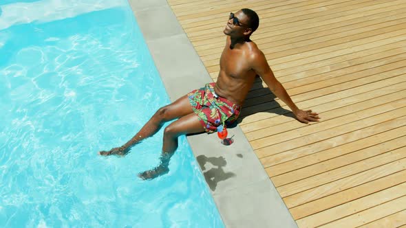 High angle viewof black man rlaaxing with his feet in swimming pool 4k