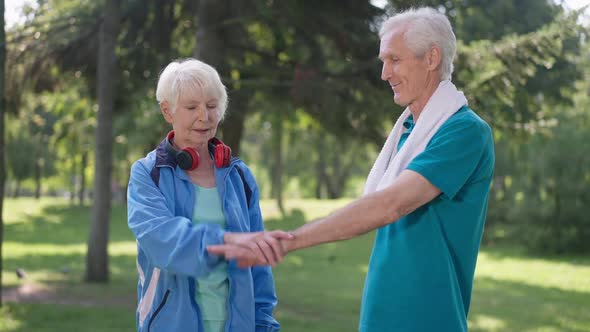 Medium Shot of Positive Senior Couple Stacking Hands in Slow Motion Smiling Standing in Park