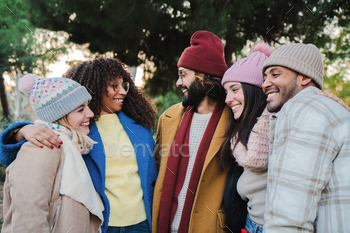 Group of young people smiling and talking outdoors with autumnal clothes. Multiracial friends having