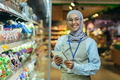 A young Arab woman in a hijab works in a supermarket, salesperson, manager. Standing with a folder - PhotoDune Item for Sale