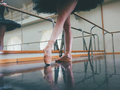 Ballerina in ballet pointe shoes stretches on barre. Woman practicing in studio - PhotoDune Item for Sale