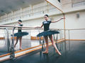 Ballerina in black tutu dress stretches on barre in ballet gym. Standing mirror - PhotoDune Item for Sale