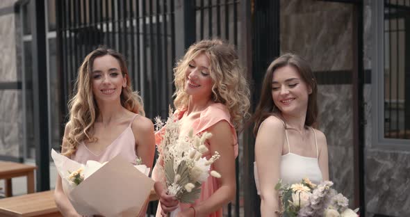 Three Hapy Ladies with Bouquets Posing in the City