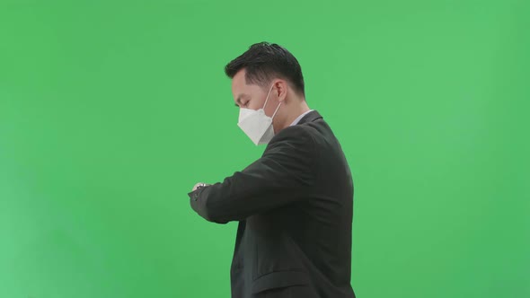 Side View Of Asian Business Man Walking And Looking At Watch On Green Screen Chroma Key