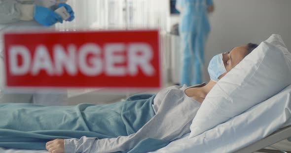 Woman Patient Lying in Bed Wearing Face Protective Mask and Doctor in Safety Suit Checking