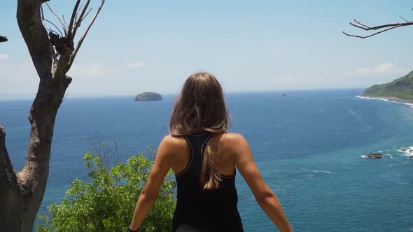 Girl Standing on a Cliff and Looking at the Sea