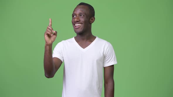 Young Happy African Man Smiling and Thinking While Pointing Up