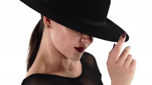 Mature Charming Woman Posing with Black Hat on White Studio Background