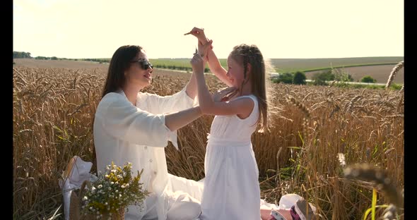 Beautiful Mother and Daughter Having Fun in a Wheat Field on Sunset