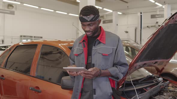 African American Mechanic Working with Tablet in Auto Service Garage