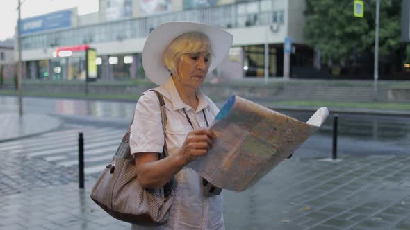 Senior Female Tourist Exploring Town with a Map in Hands. Looking for the Route