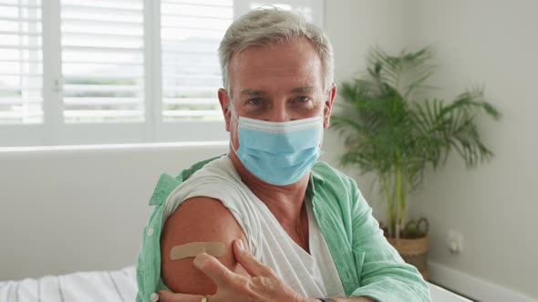 Animation of caucasian senior man wearing face mask and plaster after vaccination