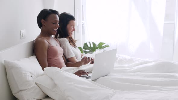 Two happy women lying in the bed at home