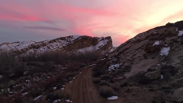 Flying over dirt road and rising above the landscape viewing colorful sunset
