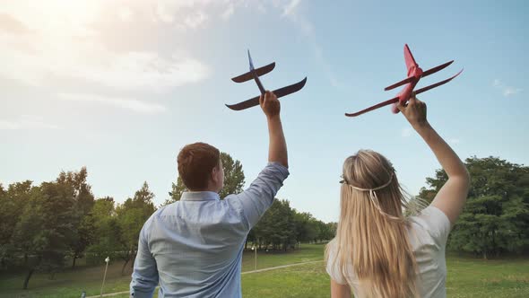 A Guy and a Girl Launch Toy Airplanes in the Sky