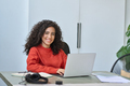 Young smiling latin business woman sitting at office desk with laptop. - PhotoDune Item for Sale