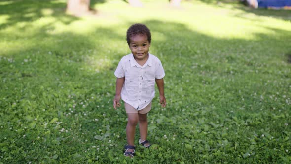 A Cute African Boy Runs in the Park and Laughs