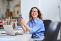 Smiling young business woman using mobile phone working in office at desk. - PhotoDune Item for Sale