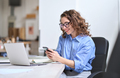 Happy young business woman using cellphone working in office sitting at desk. - PhotoDune Item for Sale