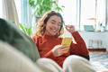 Happy relaxed young woman sitting on couch using mobile phone technology. - PhotoDune Item for Sale
