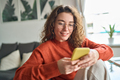 Young smiling woman using mobile phone holding cellphone at home. - PhotoDune Item for Sale