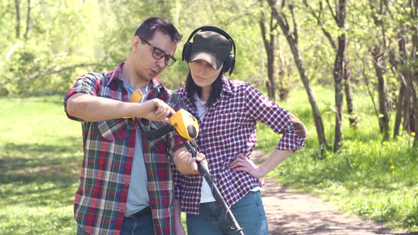 Man Treasure Hunter Explains to a Girl How to Use a Metal Detector