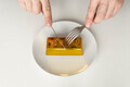 Businessman sitting with fork and knife ready to eat bar of gold served on plate - PhotoDune Item for Sale