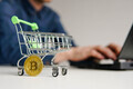 Shopping cart with bitcoin crypto currency coin on the table. Man using laptop for online trading. - PhotoDune Item for Sale
