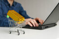 Shopping cart with gold bar on the table. Man using laptop for buying gold bars for investment. - PhotoDune Item for Sale