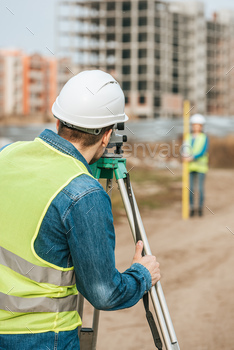 Selective focus of surveyors measuring land with digital level on construction site