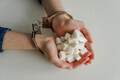 Young woman in handcuffs with white sugar cubes on the table. Sugar addiction concept. - PhotoDune Item for Sale