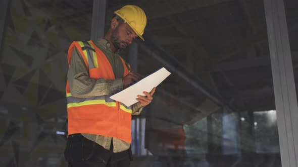 Building Surveyor with Reflective Vest Writing Notes in His Folder