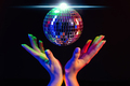 Female hand holding spinning disco mirror ball under neon. Glossy silver sphere - PhotoDune Item for Sale
