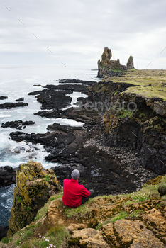 st guy sits on a rock and looks at the ocean. Famous tourist attraction of Iceland