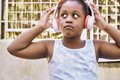 Serious black girl listening music on headphones on the street - PhotoDune Item for Sale