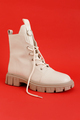 One Beige Trendy Female boot. Fashion Shoes Still Life on red background - PhotoDune Item for Sale