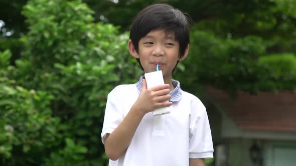 Cute Asian Child  Drinking A Carton Of Milk From A Box With A Straw 