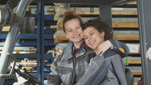 Two Cheerful Female Factory Workers Hugging Smiling Happily To the Camera