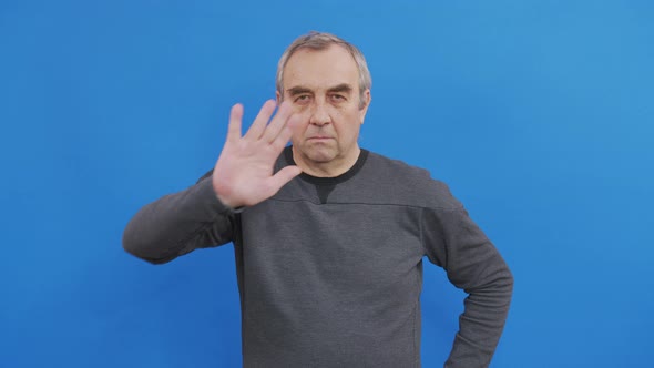 Portrait of Mature Decisive Man Puts Palm in Front of Him Confidently Shows Prohibitory Gesture Stop