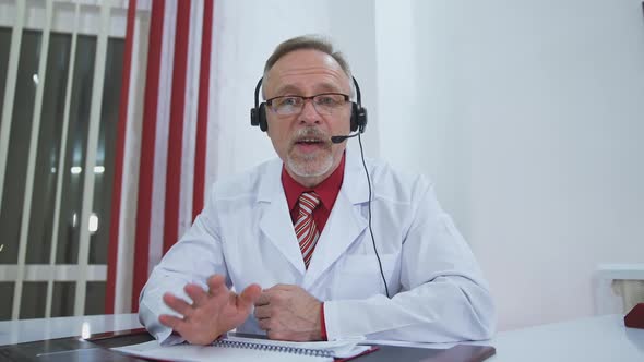 Medical specialist in headset talks on camera. 