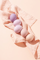 Pastel colored Easter eggs lying on linen napkin on peach background. - PhotoDune Item for Sale